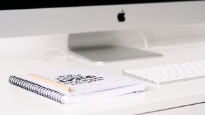 mac computer with journal and pen